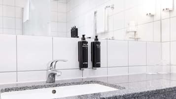 Ein modernes Badezimmer mit einem weißen Waschbecken, schwarzer Handseife und Lotion spendern.