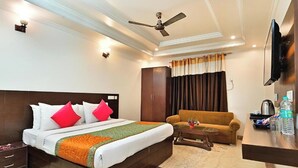 A hotel room with a bed, a sofa, a coffee table, a TV, and a wardrobe. - The Grace Hotel Near IGI Airport, New Delhi (New Delhi)