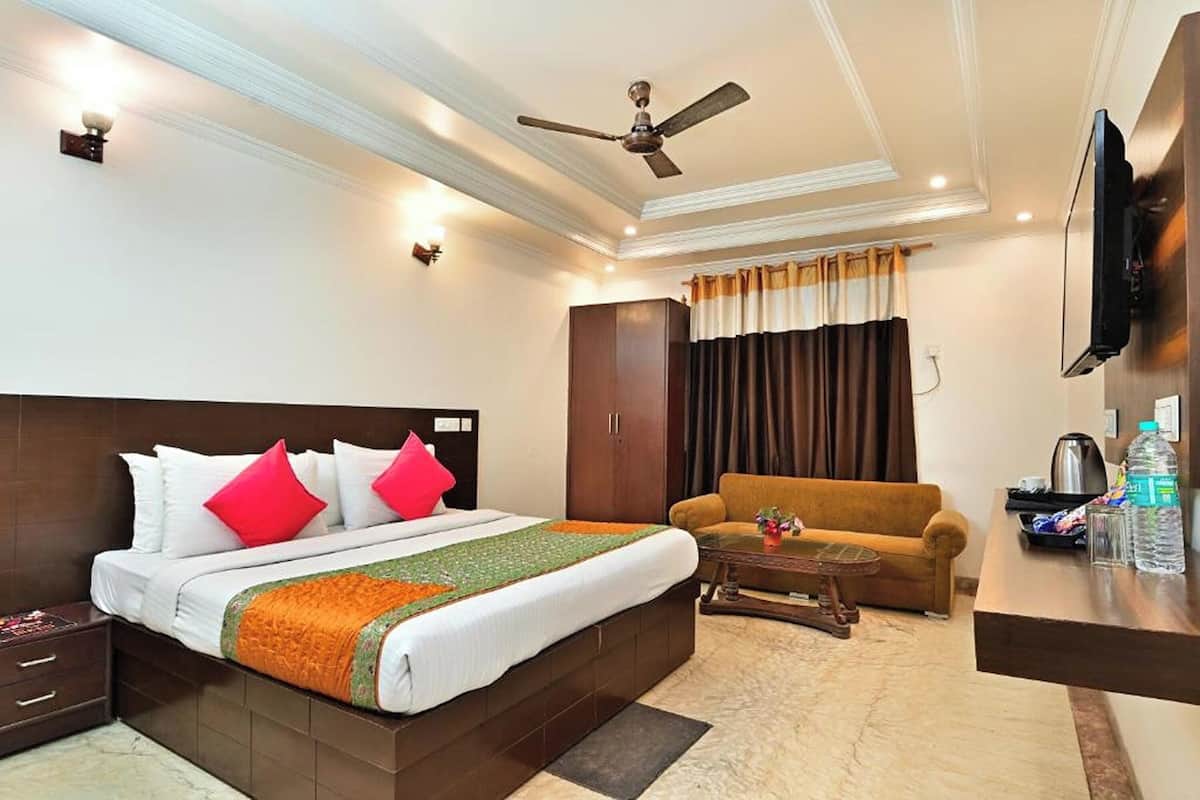 A hotel room with a bed, a sofa, a coffee table, a TV, and a wardrobe.