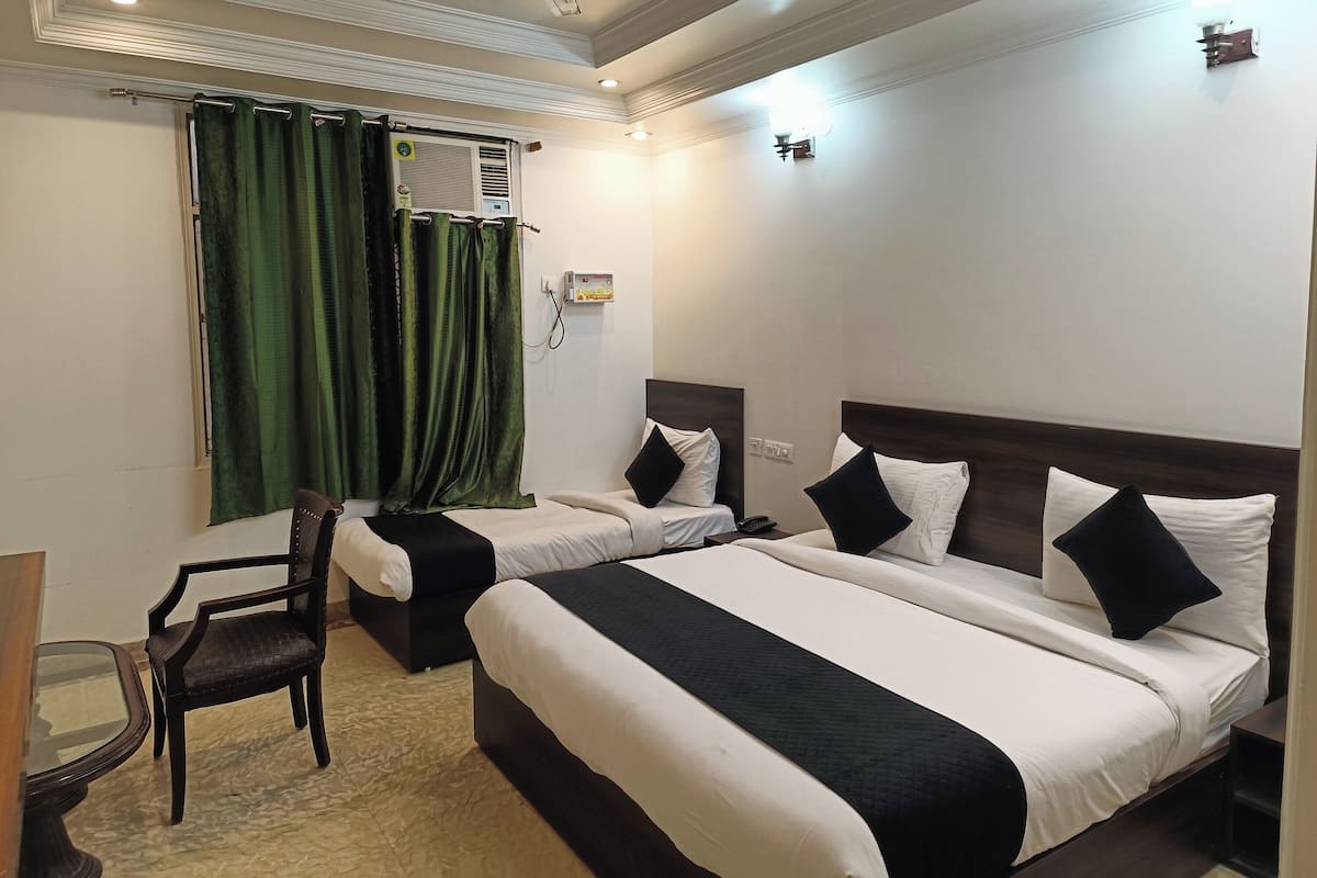 A hotel room with two beds, a chair, a small table, and a window with curtains.