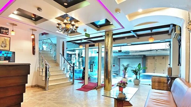A spacious lobby with a marble floor, a leather sofa, a glass coffee table, and a staircase leading to upper floors. - The Grace Hotel Near IGI Airport, New Delhi (New Delhi)