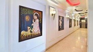 A hallway with framed artwork on the walls, a light-colored floor, and a ceiling with recessed lighting. - The Grace Hotel Near IGI Airport, New Delhi (New Delhi)