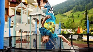 A child performing a handstand on a trampoline with a playground in the background. - Sporthotel Neustift (Neustift Im Stubaital)