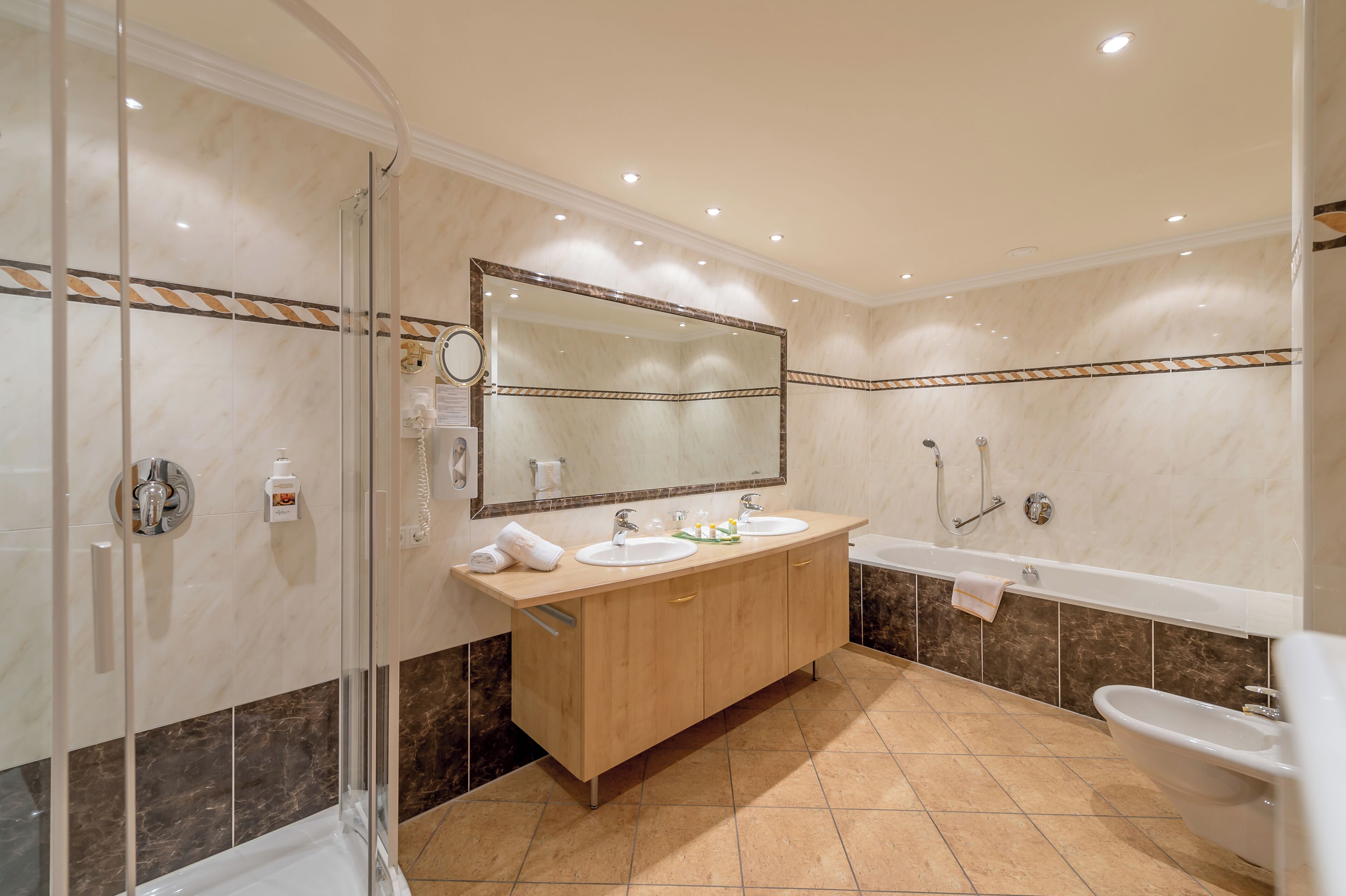 Une salle de bain dotée d’une douche à parois de verre, d’un meuble-lavabo à deux vasques, d’un grand miroir et d’une baignoire.