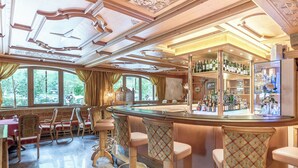 A bar area with a curved counter, bar stools, and a wine rack. - Sporthotel Neustift (Neustift Im Stubaital)