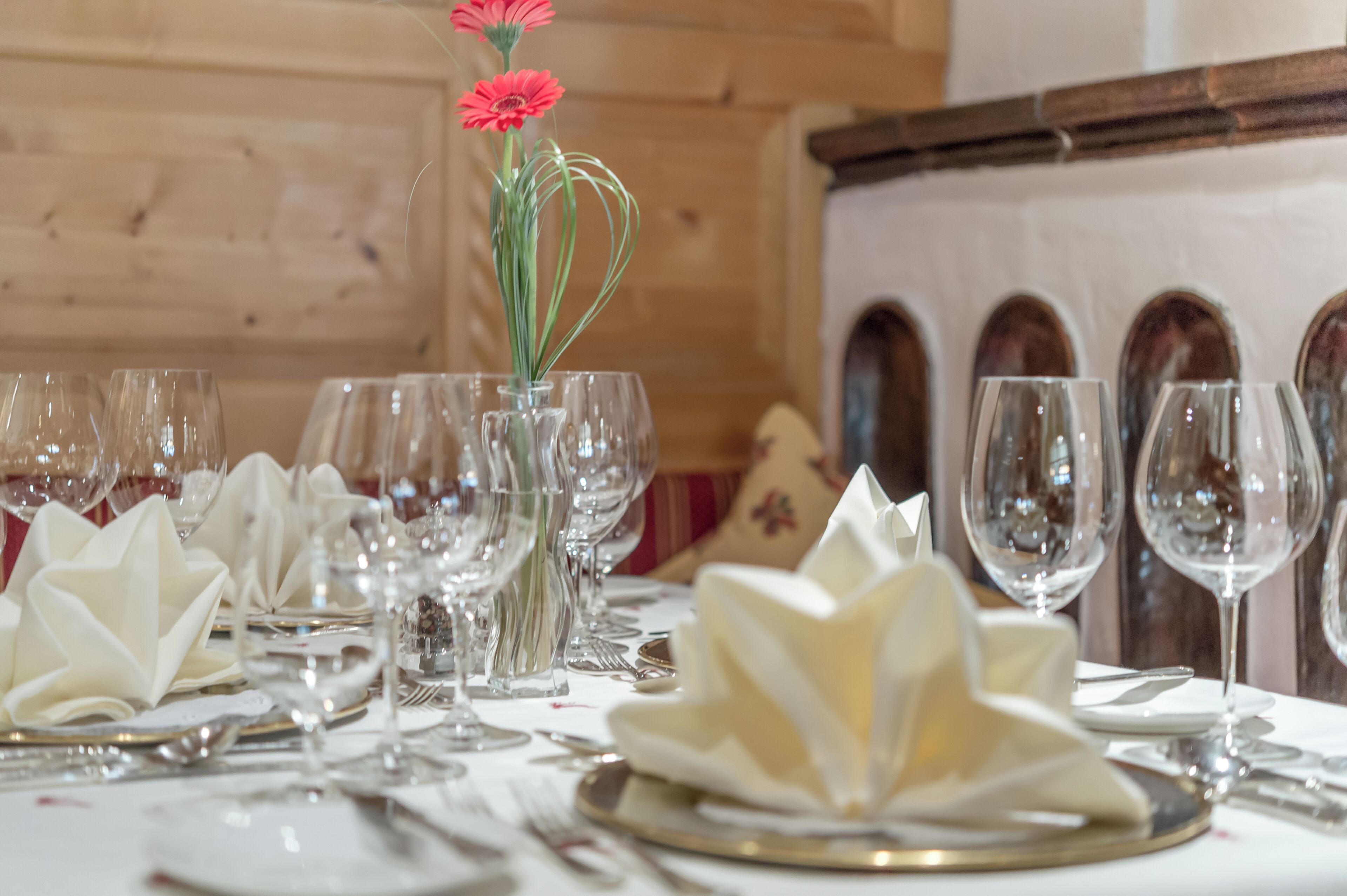 Une table dressée avec de la belle verrerie transparente, des serviettes blanches et un vase rempli de fleurs.