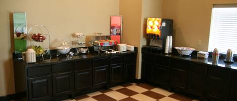 Een keuken met een geruite vloer, een buffet met diverse gerechten en een koffiehoek.