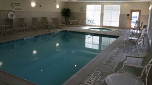 Una piscina interior con sillas de descanso y un jacuzzi.