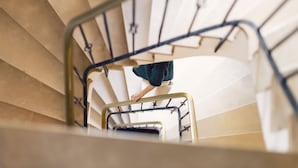 A person descending a staircase with a metal railing. - Posthotel (Valle Aurina)
