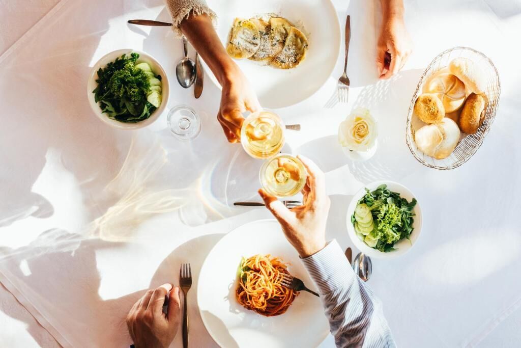 Una mesa de comedor con varios platos, vasos y una cesta de pan.