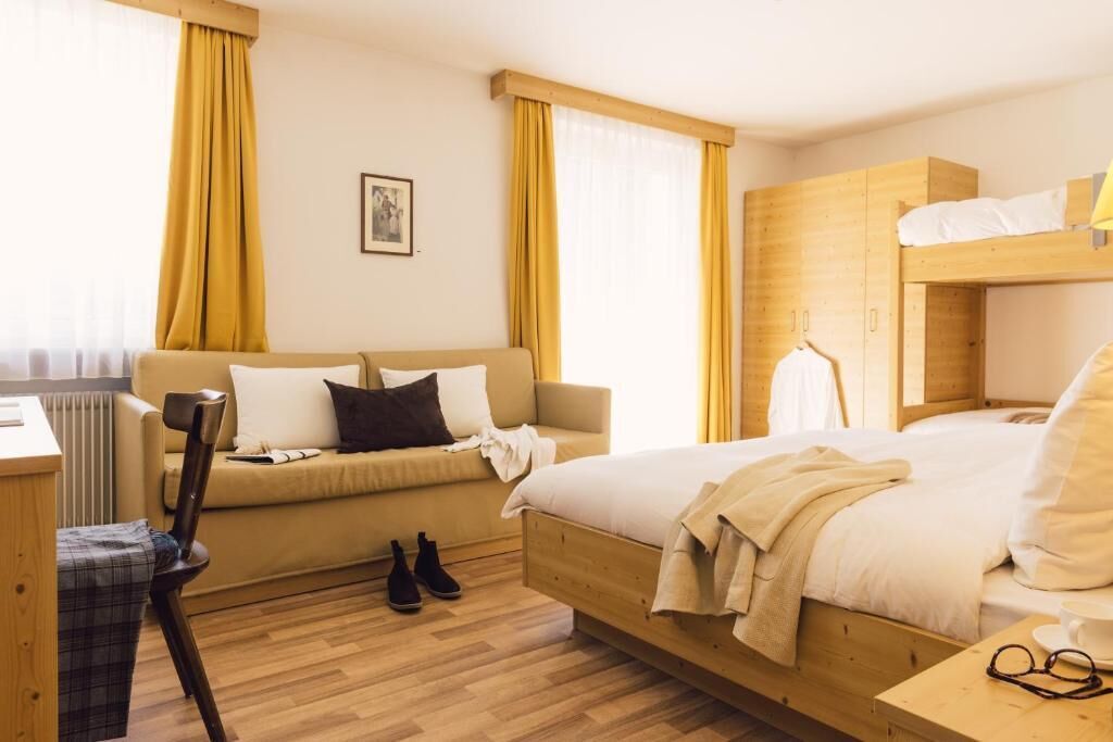 Habitació d'hotel amb un llit, un sofà, un armari de fusta i un escriptori.