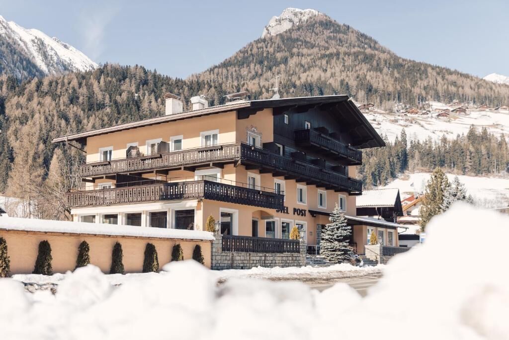 Un hôtel à plusieurs étages, doté de balcons, situé dans un cadre montagneux.