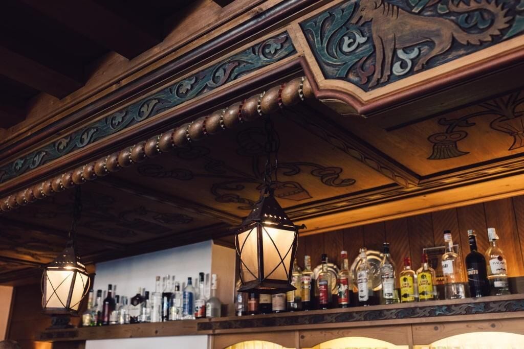 A bar area with wooden beams and a ceiling with decorative carvings.