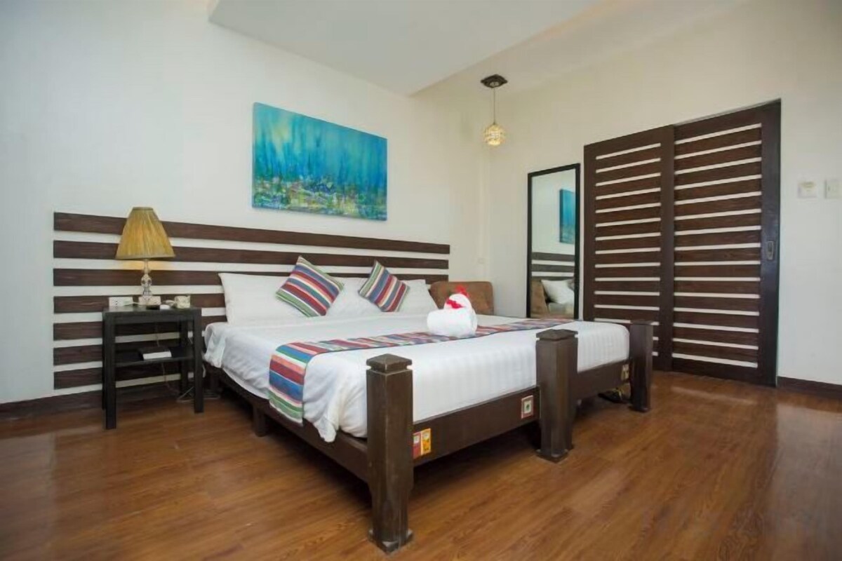 Un dormitorio con cama de madera, una mesita de noche, una lámpara, un cuadro y una puerta corredera.