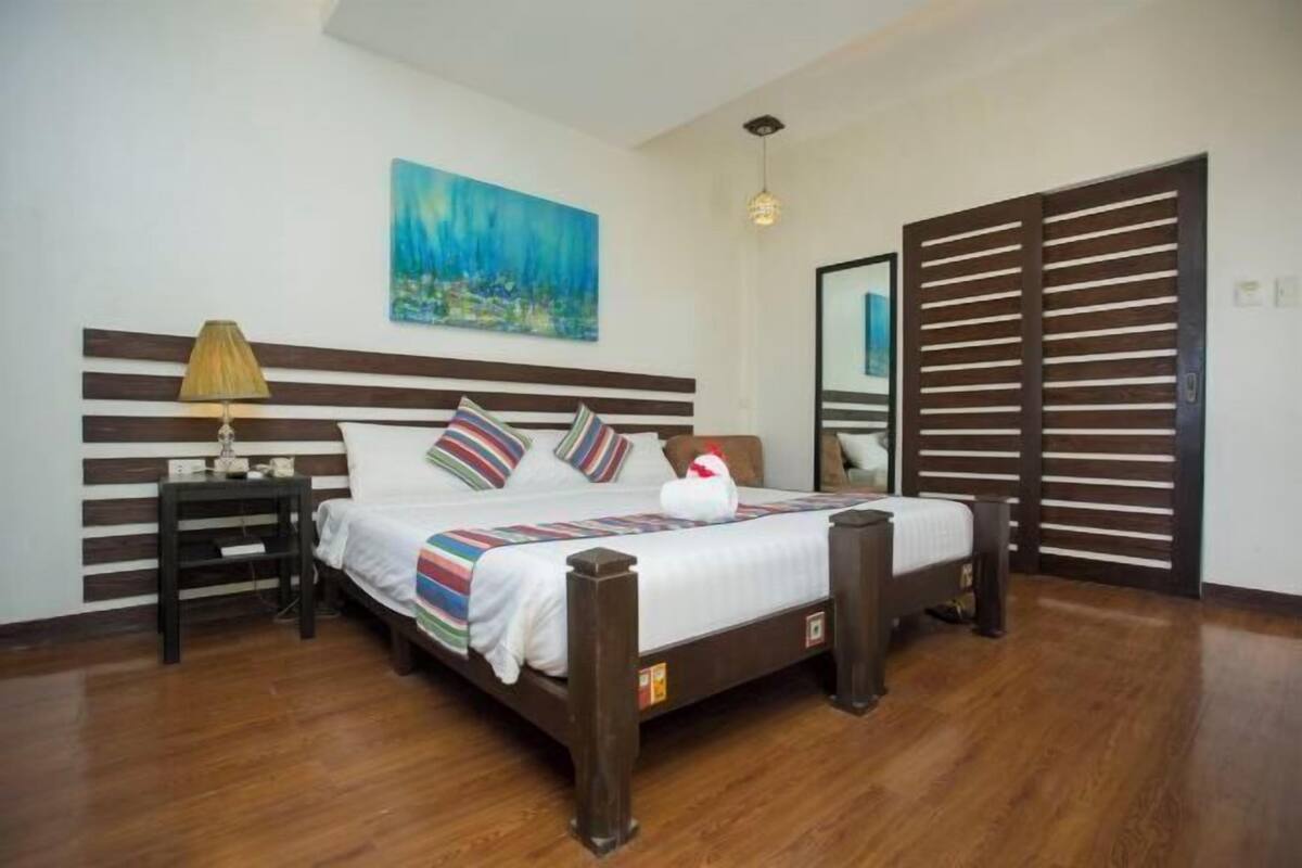 Un dormitorio con una cama, una mesita de noche, una lámpara, un cuadro y un puerta corredera.