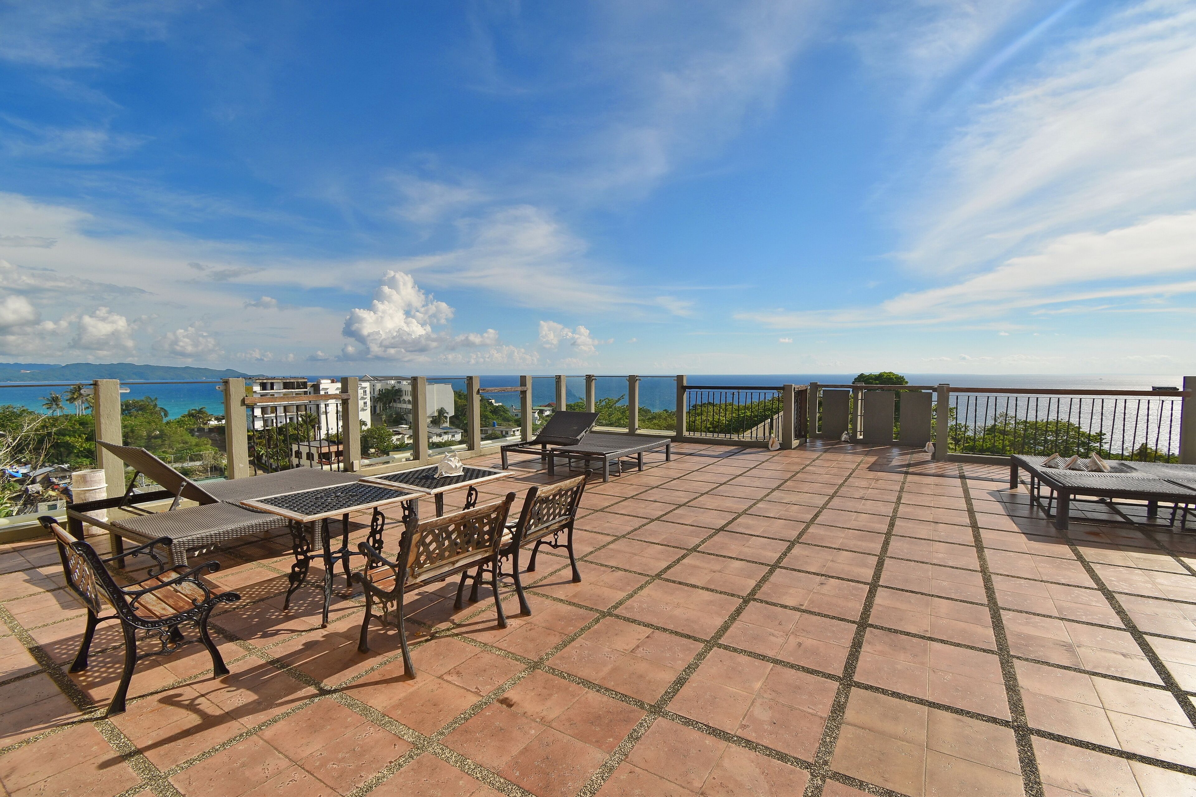 Un patio exterior con mesa y sillas, una pérgola y vista al mar.