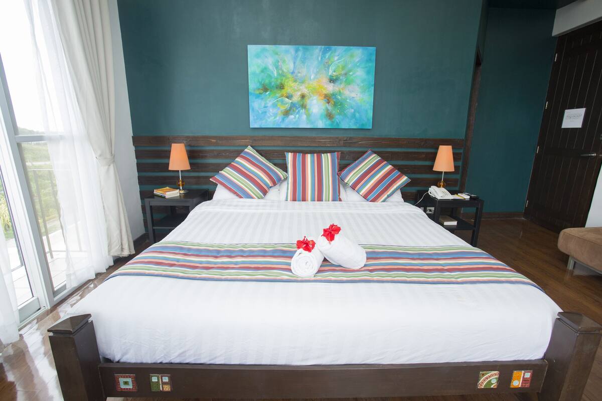 Una cama bien hecha con ropa de cama a rayas, almohadas y un par de toallas con lazos rojos.