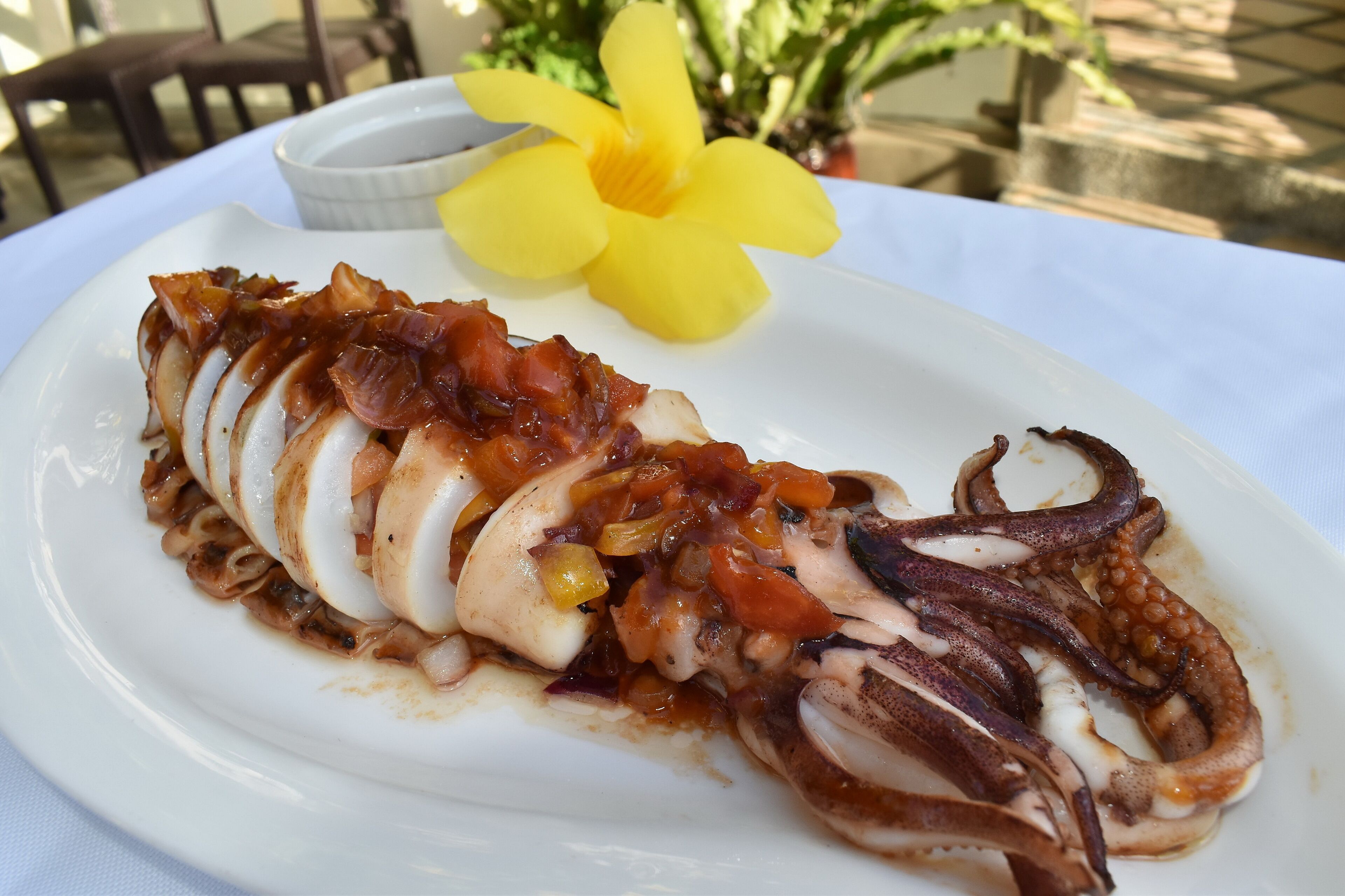 Un plato de pulpo adornado con una flor amarilla.