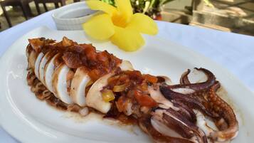 Un plato de pulpo adornado con una flor amarilla.
