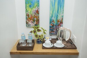 Disposição para o café da manhã com uma cafeteira, xícaras e garrafas de água sobre uma bandeja de madeira.