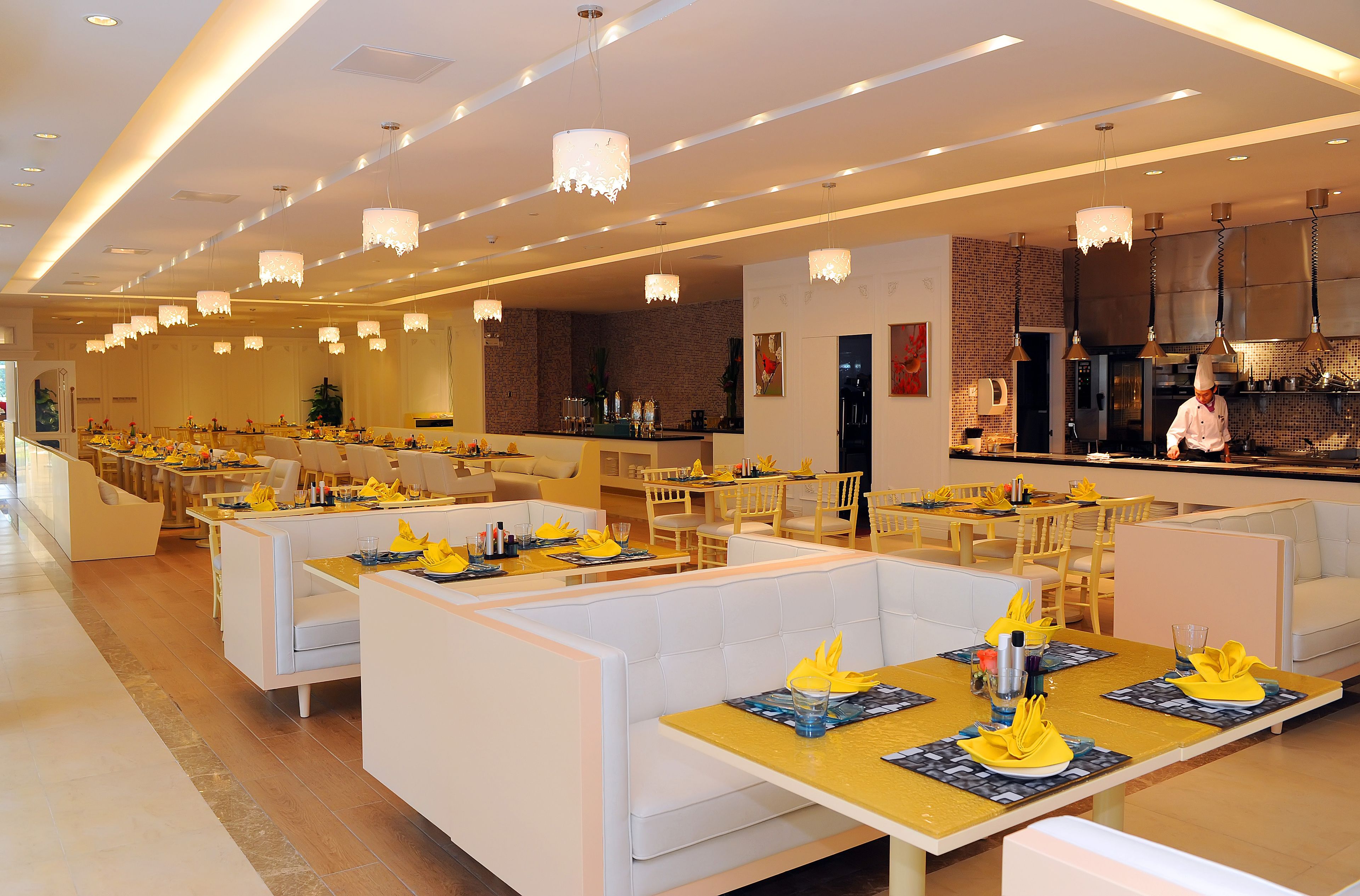 A modern restaurant with white booths and yellow table settings.