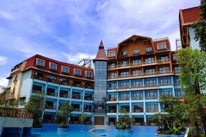 A multi-story hotel with a central atrium, balconies, and a swimming pool.