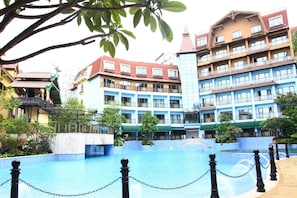 A hotel with multiple floors, balconies, and a swimming pool.