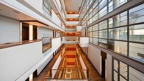A modern interior with a central glass staircase, multiple levels, and large windows. - Hilton Windhoek (Windhoek)