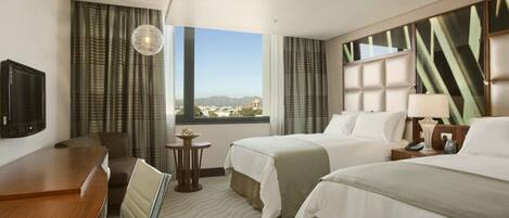 A hotel room with two beds, a desk, a chair, a TV, a small table, and a window with a view of the city.