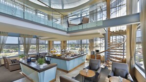 A spacious hotel lobby with a central bar area, seating arrangements, and a spiral staircase. - Hilton Windhoek (Windhoek)