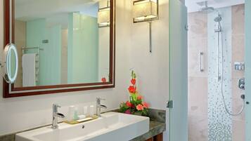 Un baño con un espejo grande, un lavamanos con encimera de mármol, una ducha con puerta de cristal y una lámpara de pared.