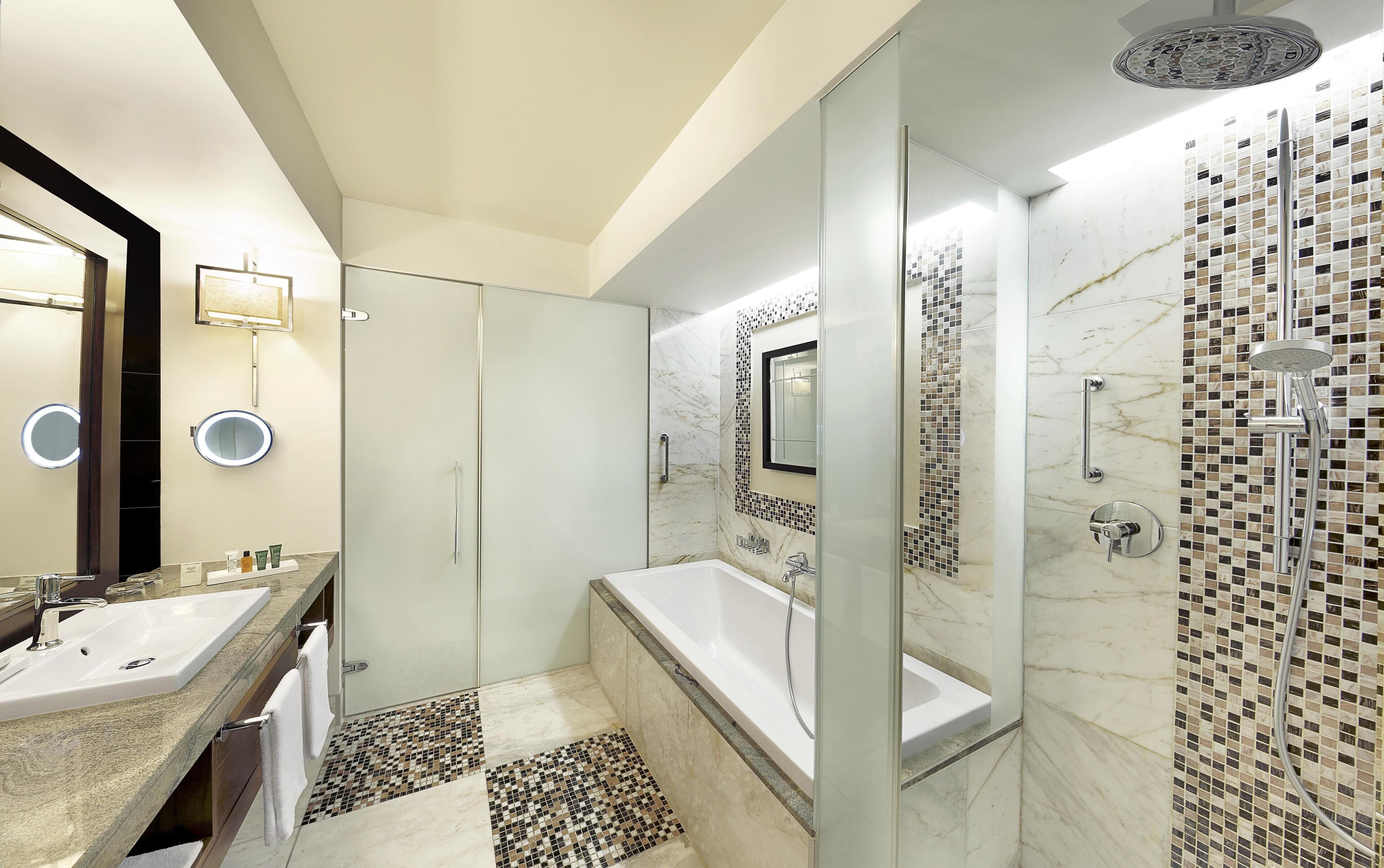 A modern bathroom with a large mirror, a bathtub, and a shower area.
