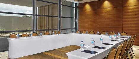 A conference room with a long table, chairs, water bottles, and a carpeted floor.