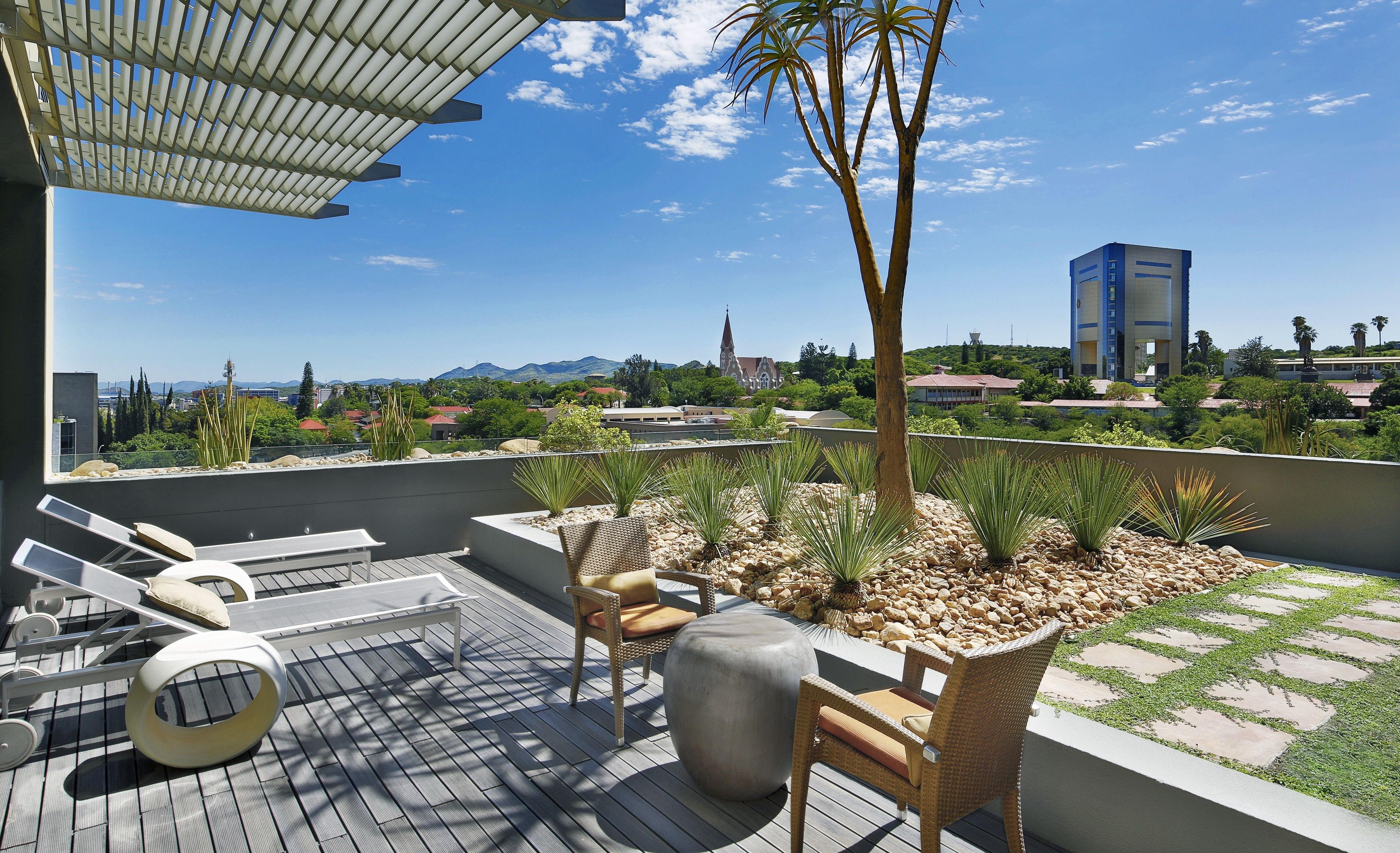 Une terrasse sur le toit, aménagée avec du mobilier d’extérieur, une pergola et offrant une vue sur le paysage urbain.