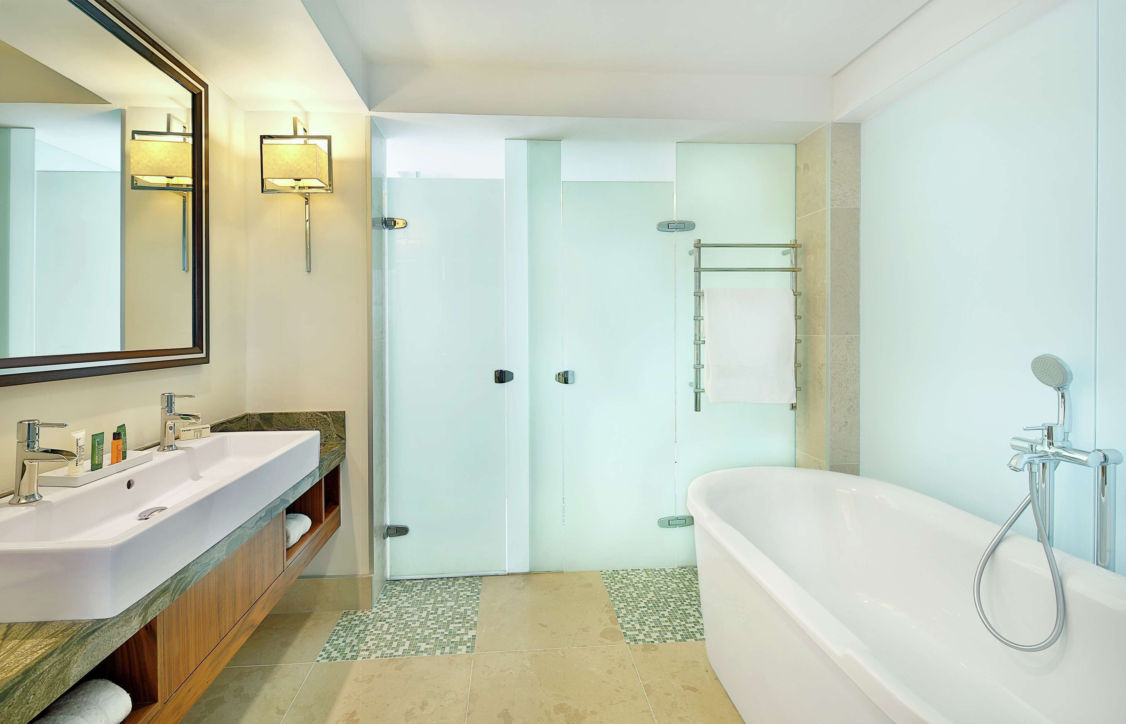 A modern bathroom with a large white bathtub, a double sink vanity, and a glass shower enclosure.
