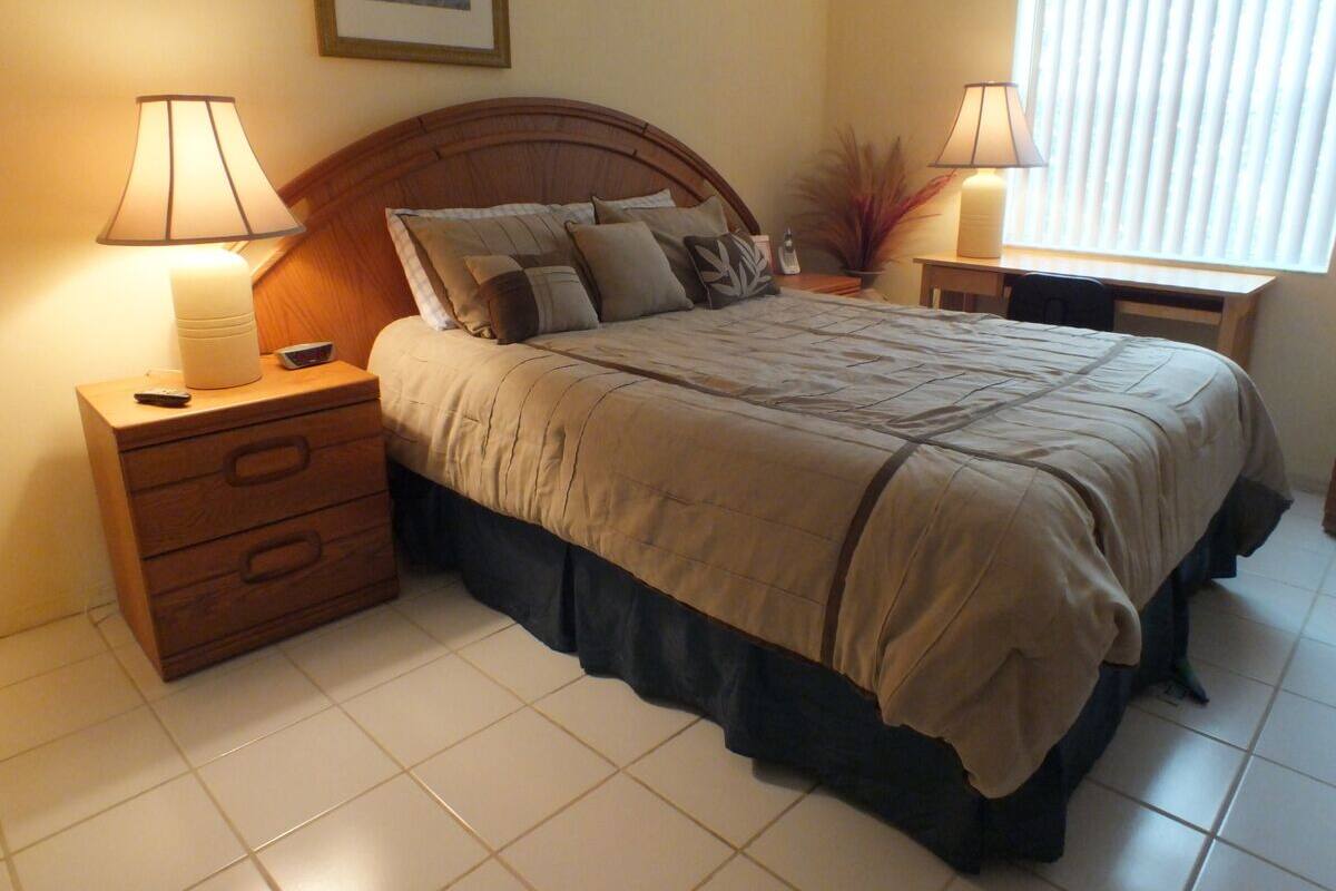 A neatly arranged bedroom with a bed, two bedside tables, and a nightstand.