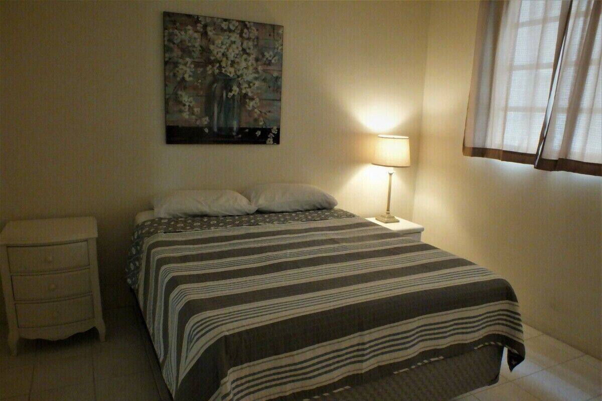 A bedroom with a bed, a nightstand, a lamp, and a painting on the wall.