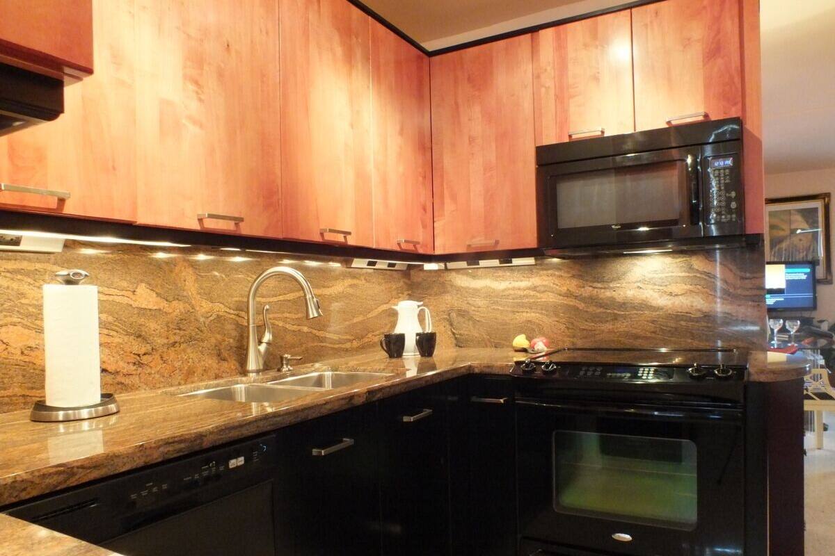 A kitchen with wooden cabinets, a stainless steel sink, a microwave, and a stove.