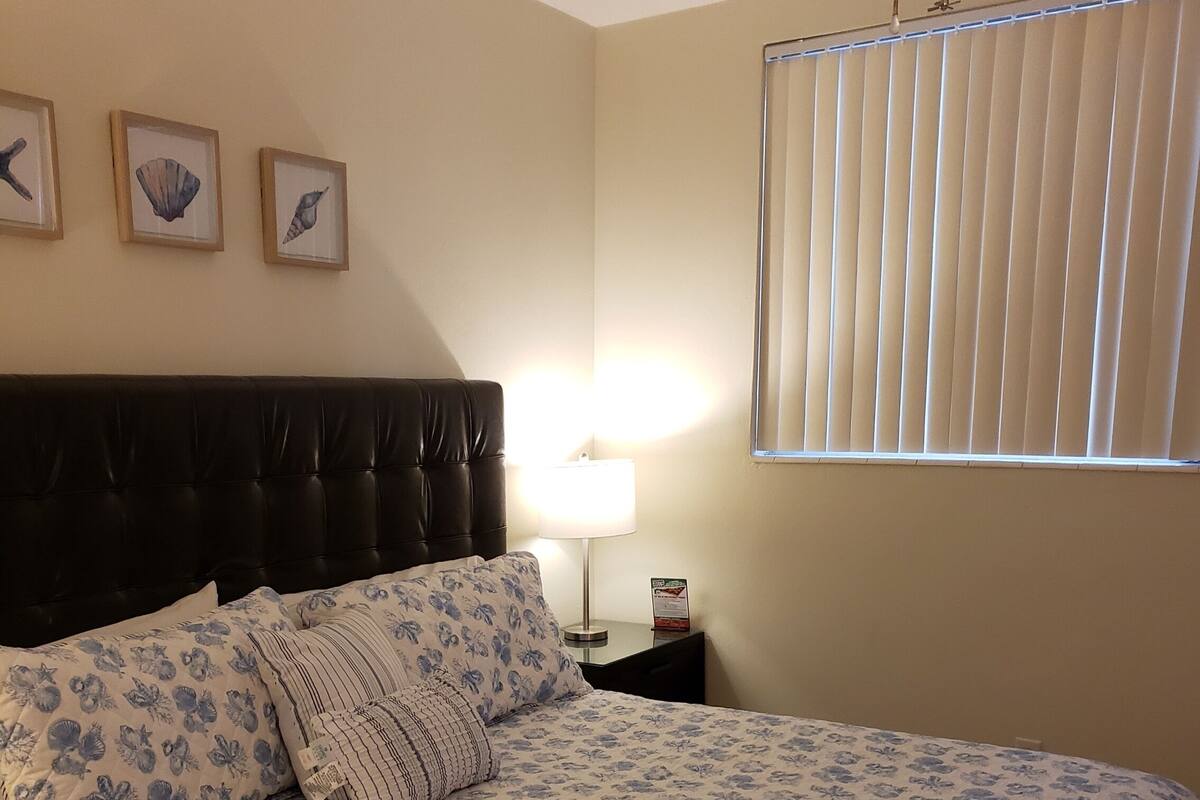 A bedroom with a bed, a nightstand, a lamp, and three framed pictures on the wall.