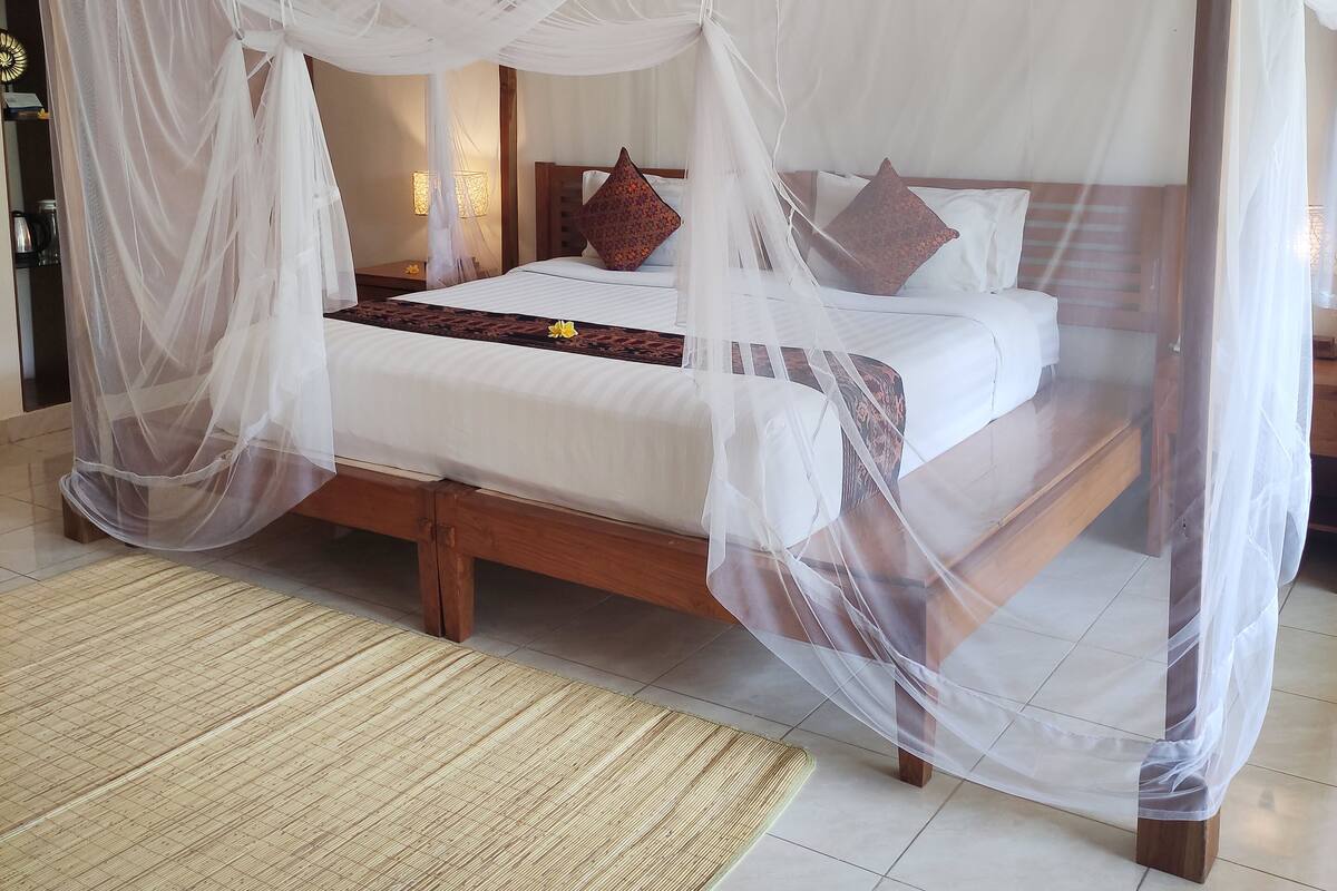 A bed with a canopy, a wooden headboard, and a patterned rug.