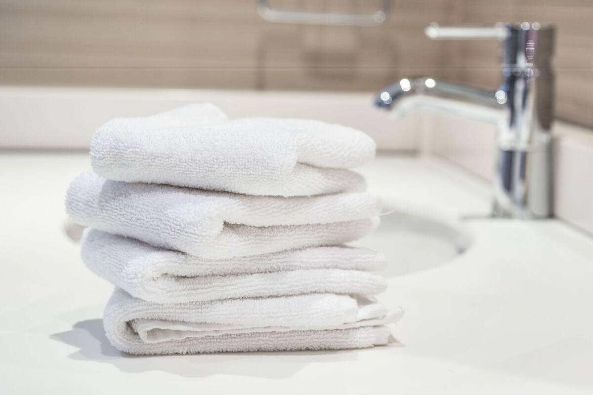 A stack of white towels on a bathroom sink with a modern faucet.