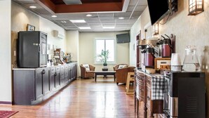 Una cocina moderna con refrigerador, estufa y cafetera. Hay un comedor con mesa y sillas.