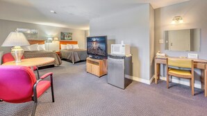 A hotel room with a bed, a desk with a chair, a television, and a refrigerator. - The Gables inn (Sarnia)