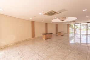 A spacious lobby with marble flooring, wooden benches, and a large window offering a view of the outdoors. - Hotel Inter Cuiabá (Cuiabá)