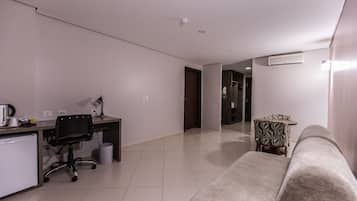 Quarto de hotel moderno com cozinha compacta, uma escrivaninha com cadeira, um sofá e uma mesa estampada.