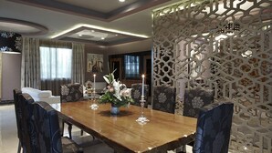 Een eetgedeelte met een houten tafel, stoelen en een decoratieve scheidingswand.