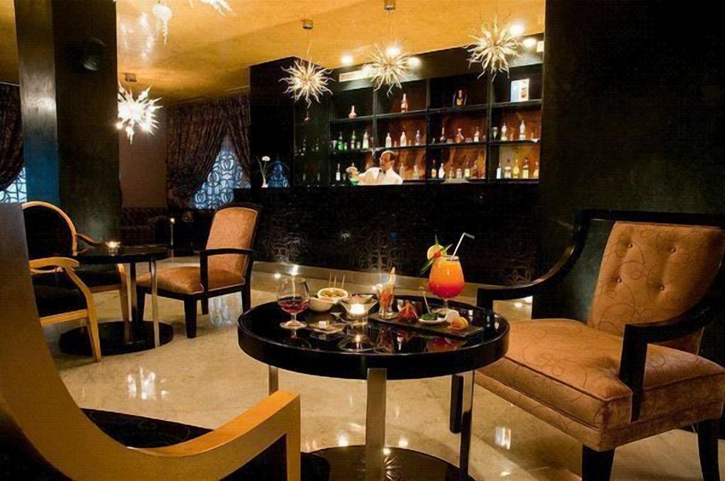 A bar area with a round table, chairs, and a bar stocked with bottles.