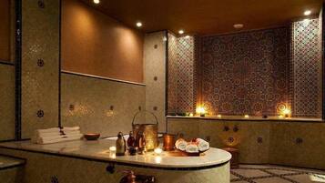 Bathroom features a central sink, large mirror, and intricate tile patterns.