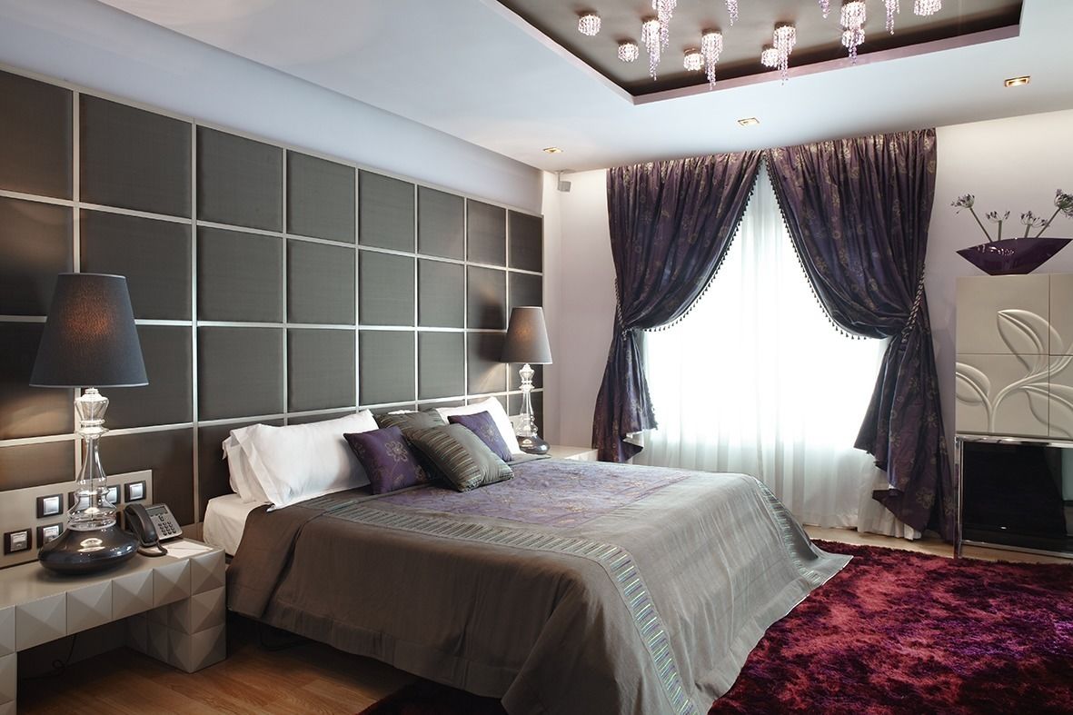 A modern hotel room with a large bed, two bedside tables, a flat-screen TV, and a chandelier.