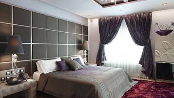 Une chambre d’hôtel moderne dotée d’un grand lit, de deux tables de chevet, d’un téléviseur à écran plat et d’un lustre.